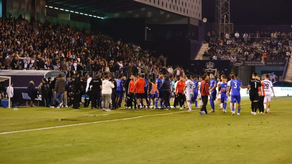 Los jugadores del Real Jaén y del Linares Deportivo se dirigen a vestuarios tras la decisión arbitral de suspender el partido por los altercados del derbi.