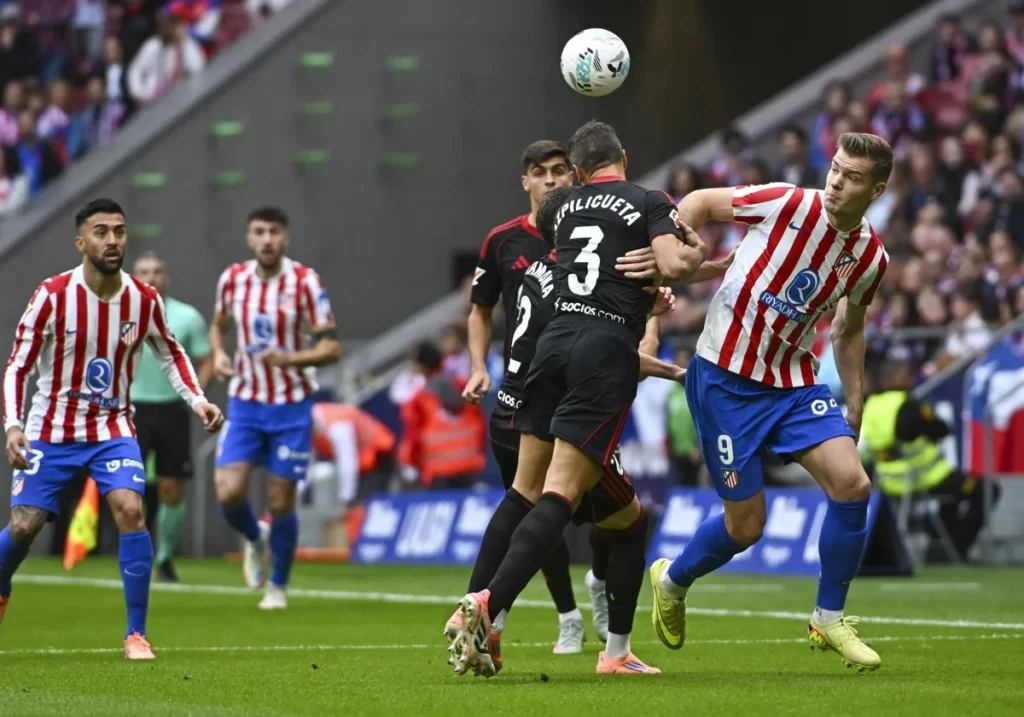 Azpilicueta (Sevilla FC) y Sorloth (Atlético de Madrid) disputan un balón aéreo en el centro del campo.