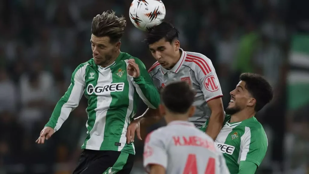 Giovanni Lo Celso disputa con la cabeza un balón aéreo ante un futbolista del Olympique de Lyon al que marca de cerca Pablo Fornal.