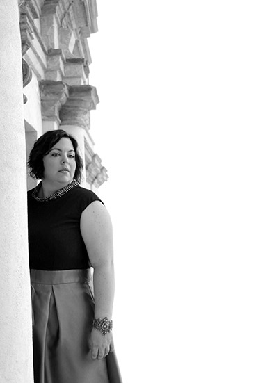 Rossana Franzese asomada por una columna mirando de reojo. 