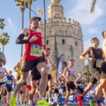 Varios corredores a su paso frente a la Torre del Oro poco después de tomar la salida de la Maratón de Sevilla