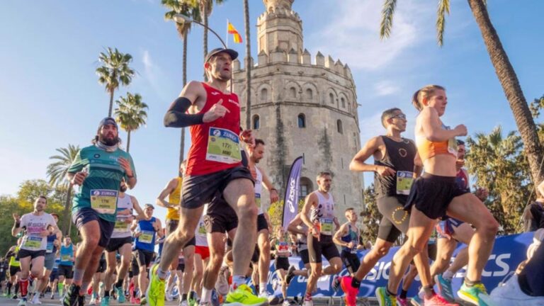Varios corredores a su paso frente a la Torre del Oro poco después de tomar la salida de la Maratón de Sevilla