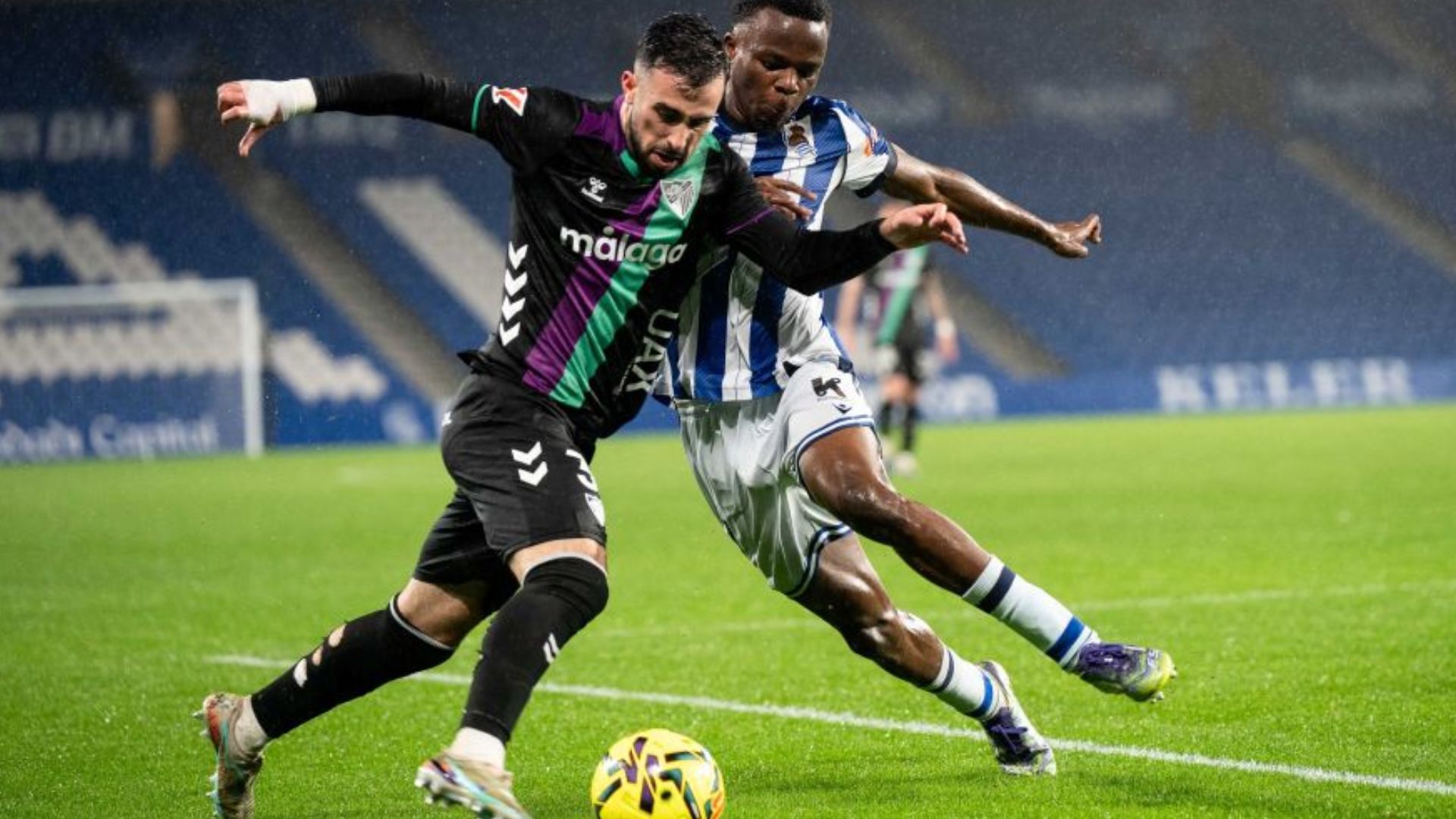 Carlos Puga trata de alcanzar la línea de fondo ante la presión de un defensa de la Real Sociedad B. El equipo malagueño acabó derrotado en Anoeta en el último partido de la jornada 26 de la Liga Hypermotion